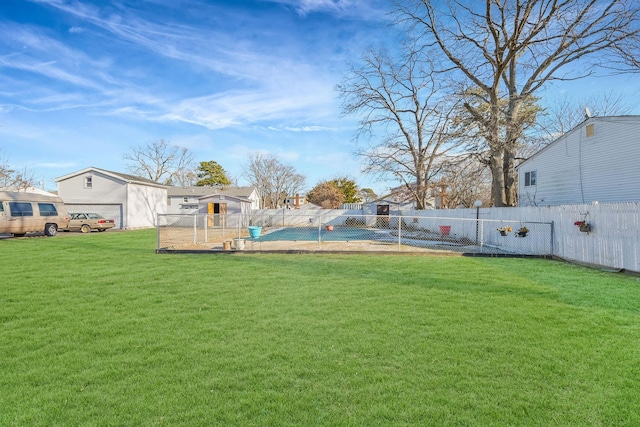 view of yard with a garage, a fenced in pool, and an outbuilding