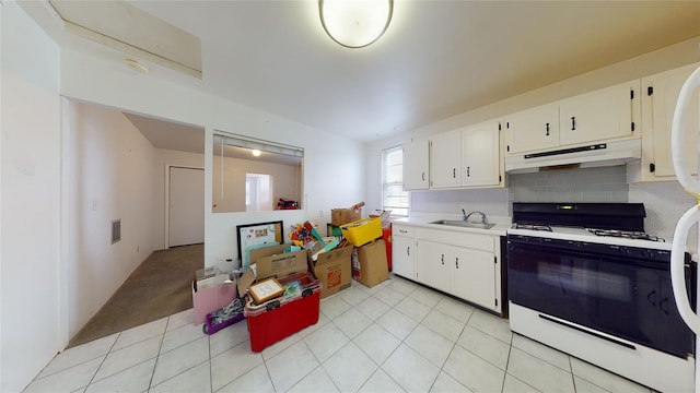 kitchen featuring sink, white gas range, light tile patterned floors, tasteful backsplash, and white cabinetry