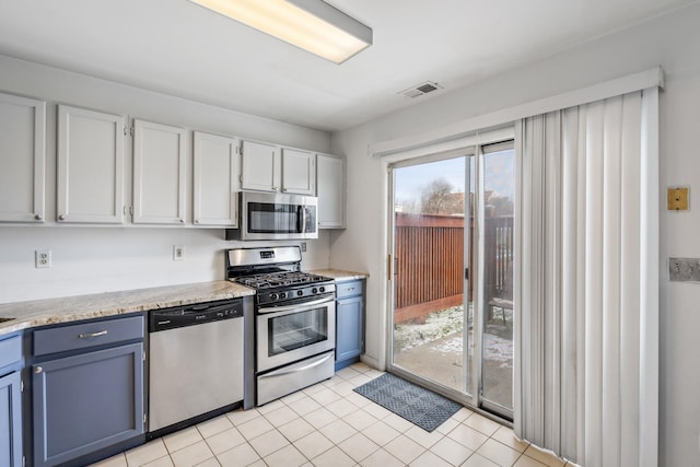 kitchen with blue cabinets, stainless steel appliances, light tile patterned floors, and white cabinets