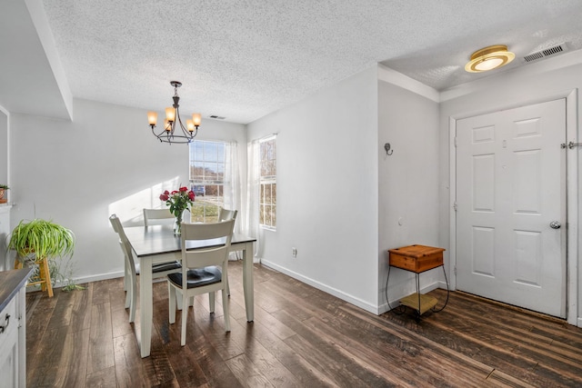 dining space with dark wood-type flooring, a textured ceiling, and a notable chandelier