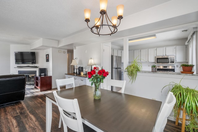 dining space with dark hardwood / wood-style flooring, a textured ceiling, and a notable chandelier