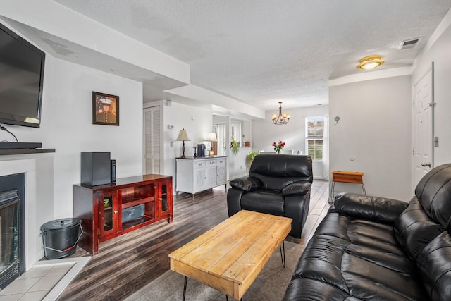 living room featuring a textured ceiling, a chandelier, a fireplace, and wood-type flooring