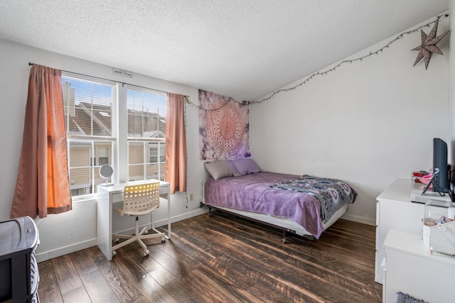 bedroom with a textured ceiling and dark hardwood / wood-style flooring