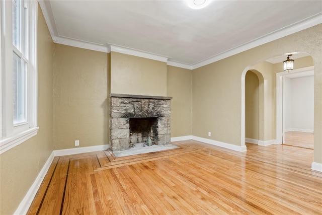 unfurnished living room with a stone fireplace, wood-type flooring, and ornamental molding