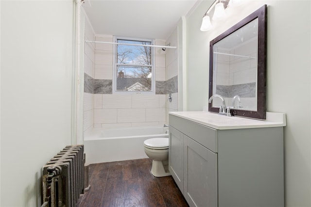 full bathroom featuring radiator, tiled shower / bath combo, hardwood / wood-style floors, toilet, and vanity