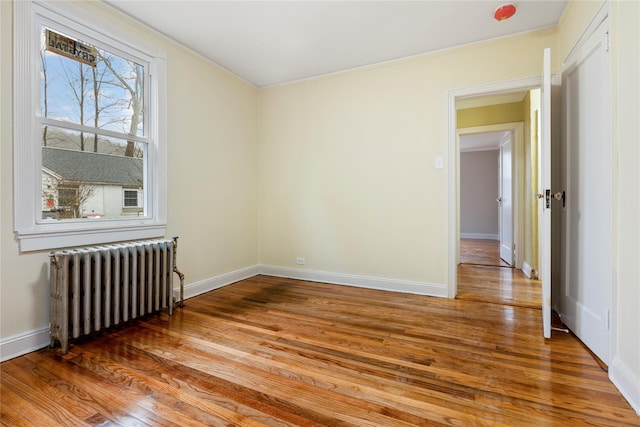 unfurnished room with radiator and wood-type flooring