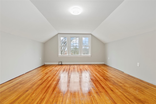 bonus room with light wood-type flooring and vaulted ceiling