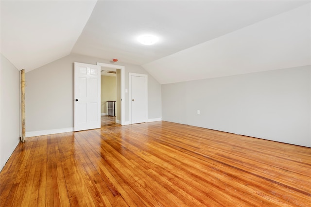 additional living space with light wood-type flooring and vaulted ceiling