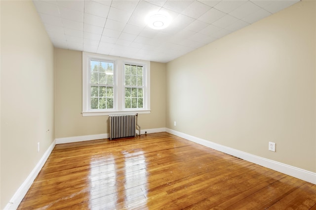 spare room featuring light wood-type flooring and radiator