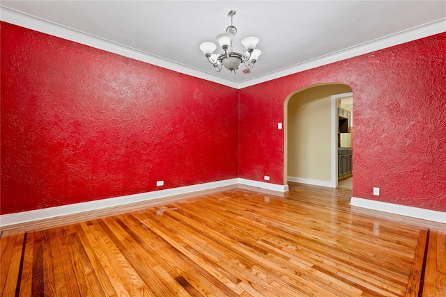 unfurnished room featuring hardwood / wood-style floors, ornamental molding, and a notable chandelier