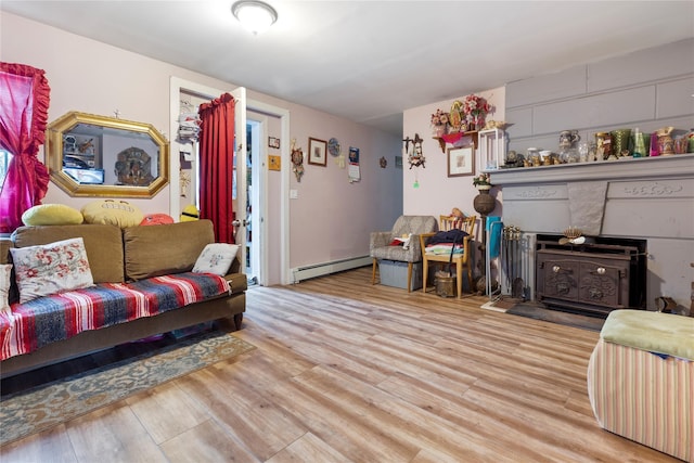 living room with a wood stove, light hardwood / wood-style flooring, and a baseboard radiator