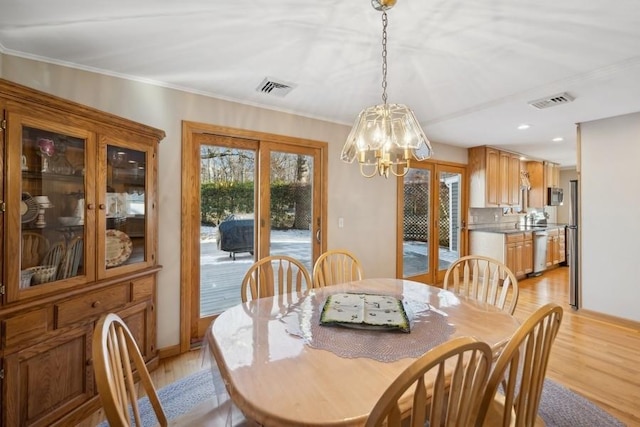 dining space with ornamental molding, light hardwood / wood-style flooring, and a chandelier