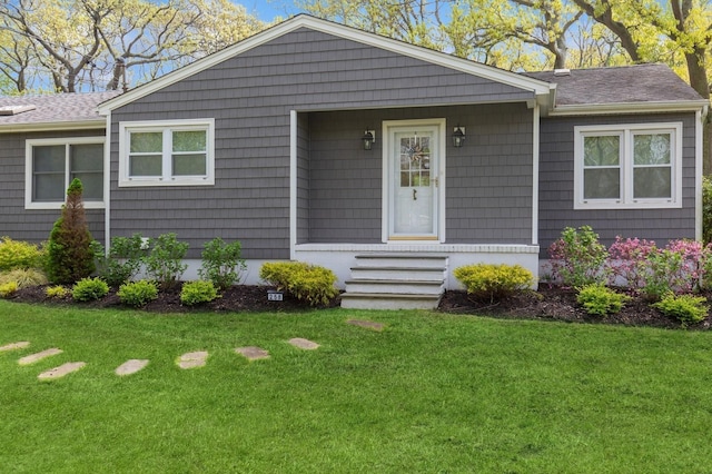 ranch-style house with a front yard, a shingled roof, and entry steps