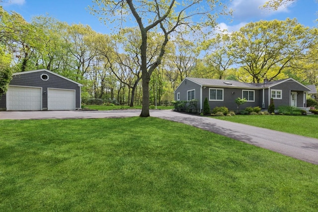 view of front of house with a detached garage, an outdoor structure, and a front yard