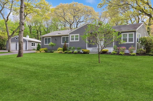 single story home with a front yard, an outbuilding, roof with shingles, and a garage