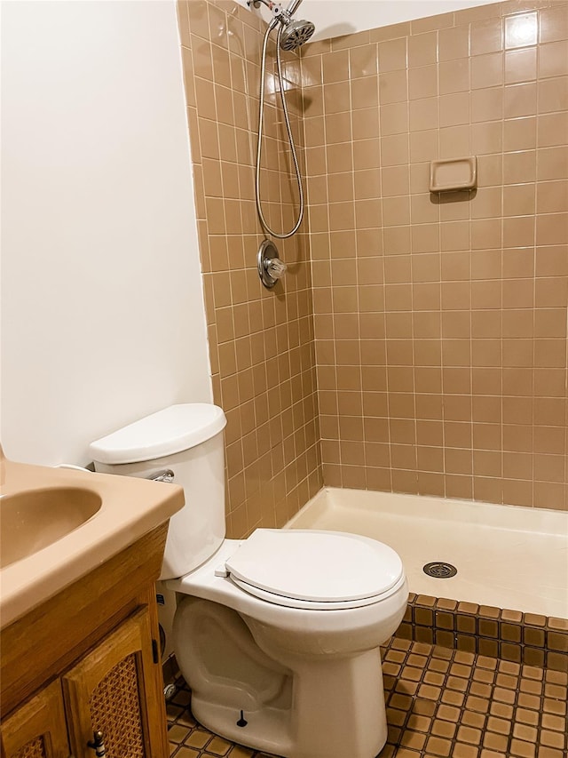 bathroom featuring tiled shower, tile patterned flooring, vanity, and toilet