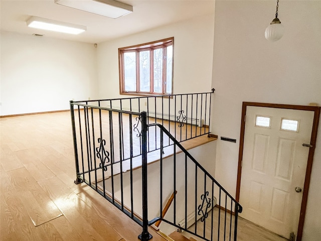 stairway with hardwood / wood-style floors and baseboard heating