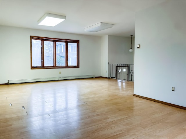 empty room with a baseboard radiator and light hardwood / wood-style floors