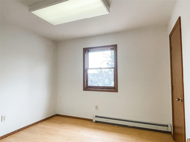 empty room with light hardwood / wood-style flooring and a baseboard heating unit