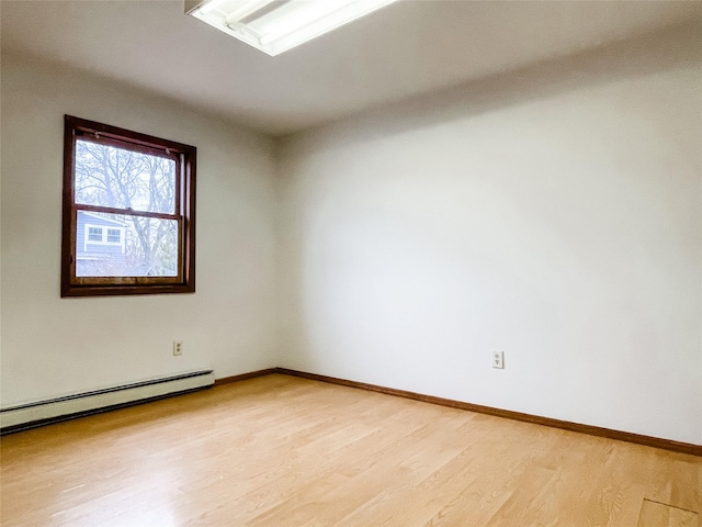 empty room featuring a baseboard radiator and light hardwood / wood-style flooring