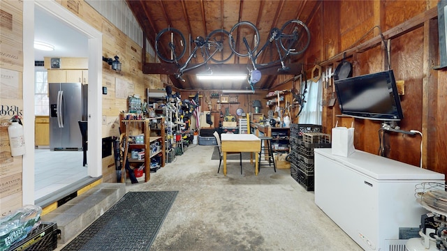 misc room featuring vaulted ceiling, wood walls, concrete floors, wood ceiling, and a workshop area