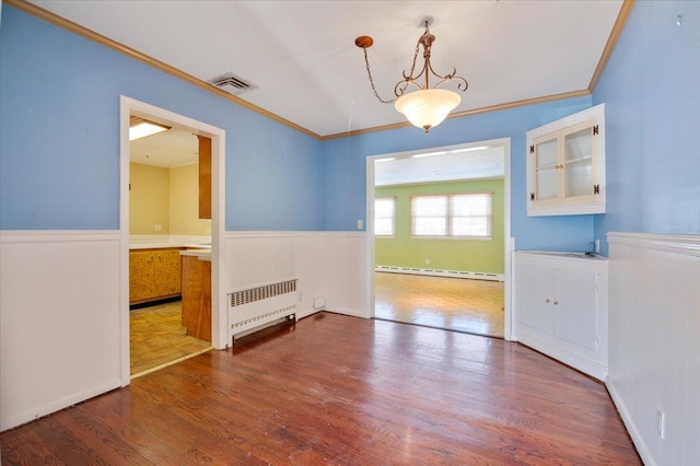 unfurnished dining area with crown molding, wood-type flooring, radiator heating unit, and baseboard heating