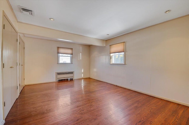 unfurnished living room with radiator heating unit and wood-type flooring