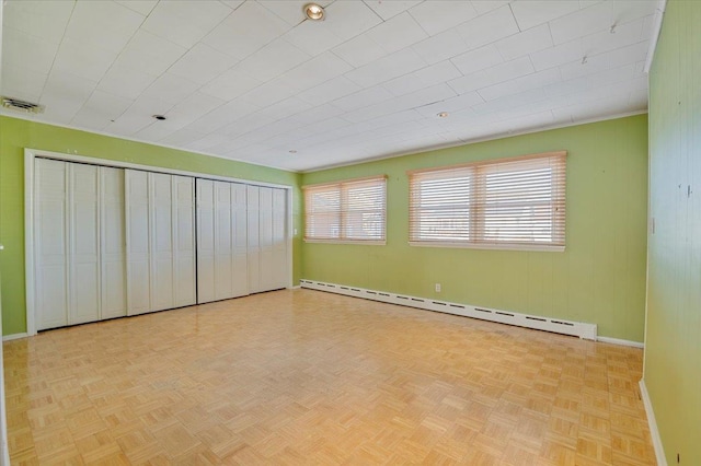 unfurnished bedroom with light parquet flooring and baseboard heating