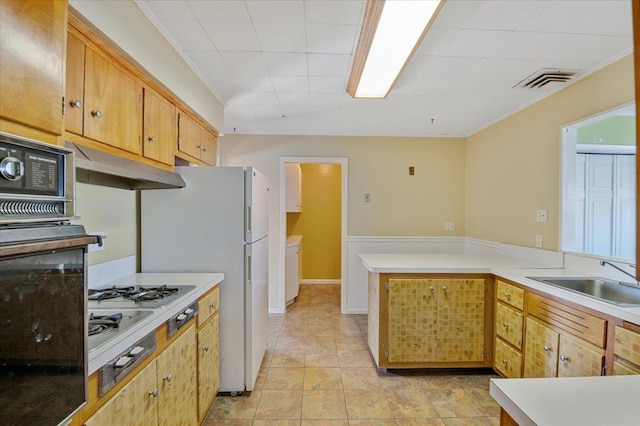 kitchen with kitchen peninsula, sink, white refrigerator, black oven, and stainless steel gas stovetop