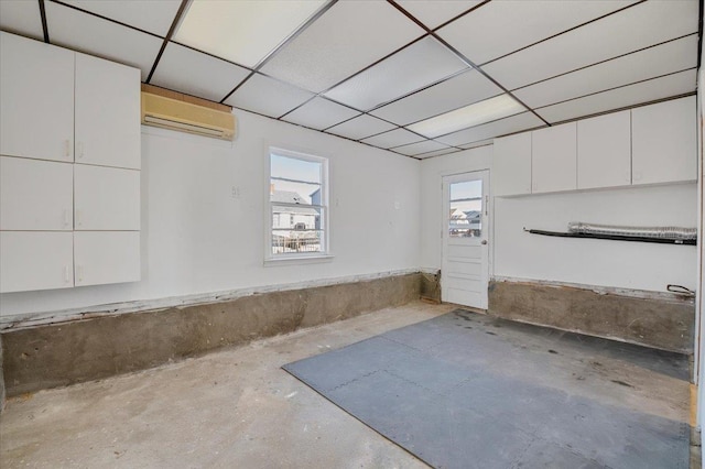 basement featuring a wall unit AC and a drop ceiling