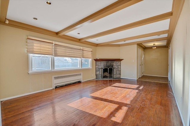 unfurnished living room with a fireplace, radiator heating unit, beamed ceiling, and hardwood / wood-style floors