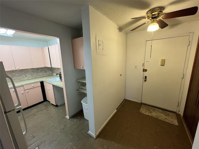 kitchen with backsplash, ceiling fan, sink, white cabinets, and fridge