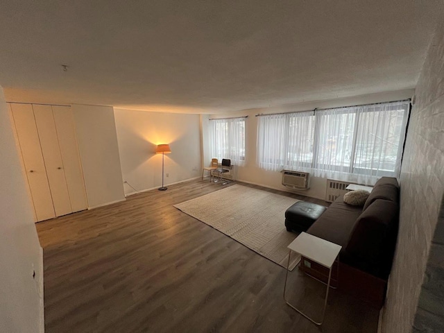 unfurnished living room with radiator heating unit, dark wood-type flooring, and a wall unit AC