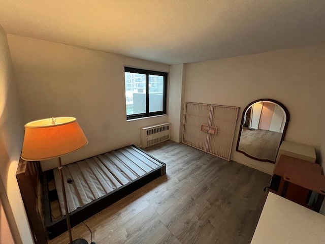 bedroom with hardwood / wood-style flooring and radiator