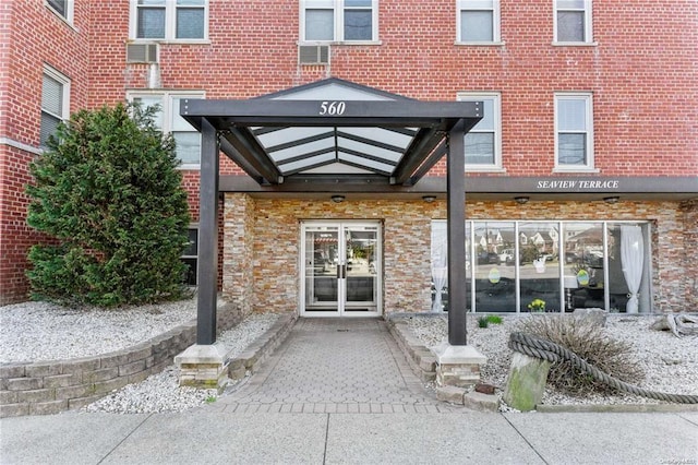 view of exterior entry featuring french doors and a wall mounted AC