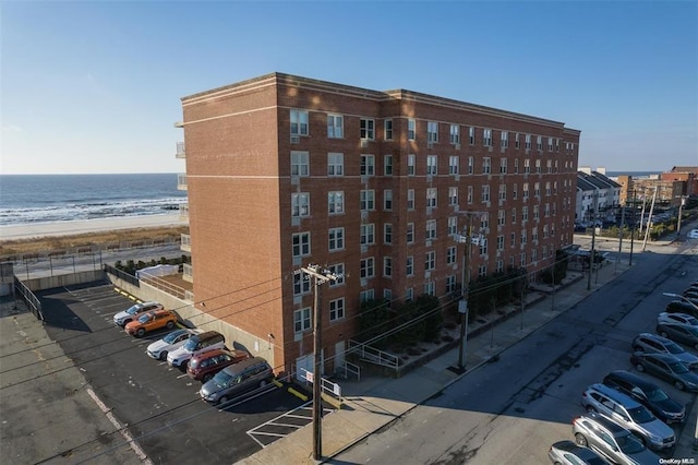 view of property featuring a view of the beach, uncovered parking, and a water view