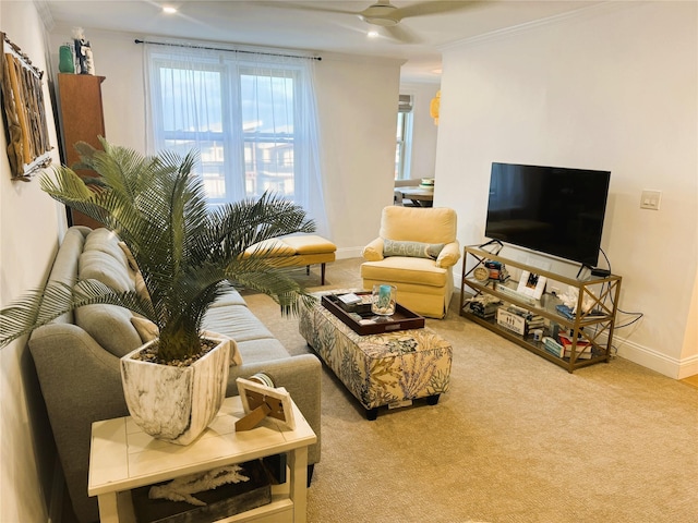 living room with a ceiling fan, carpet floors, crown molding, and baseboards