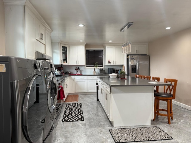 kitchen with stainless steel fridge with ice dispenser, white cabinets, decorative light fixtures, washer and dryer, and a breakfast bar area