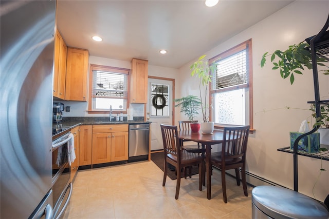 kitchen featuring stainless steel appliances, sink, light tile patterned floors, a baseboard heating unit, and dark stone counters