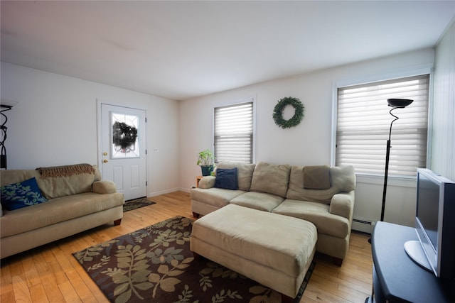 living room with a baseboard heating unit and light hardwood / wood-style flooring