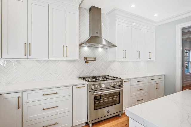 kitchen featuring light stone countertops, backsplash, wall chimney exhaust hood, high end stainless steel range, and white cabinetry