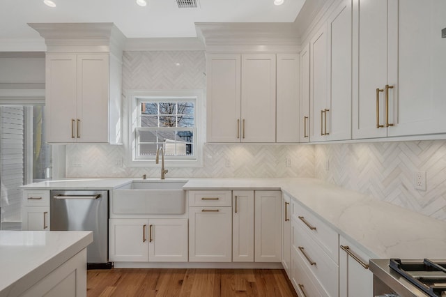 kitchen with dishwasher, backsplash, white cabinets, sink, and light stone countertops