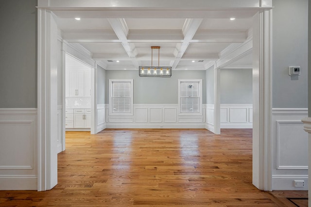 empty room featuring beam ceiling, wood-type flooring, crown molding, and coffered ceiling