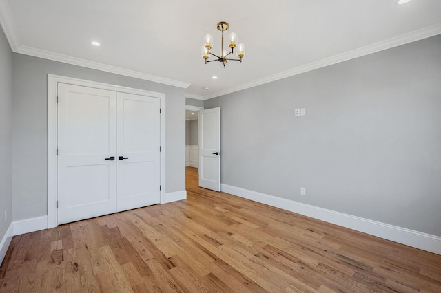 unfurnished bedroom featuring light hardwood / wood-style flooring, crown molding, a closet, and a notable chandelier