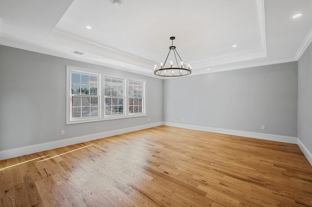 unfurnished dining area featuring a raised ceiling, light hardwood / wood-style flooring, ornamental molding, and a notable chandelier