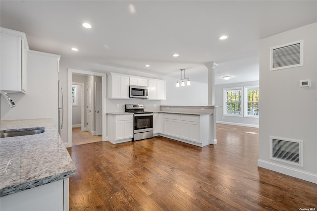 kitchen featuring dark wood-type flooring, visible vents, appliances with stainless steel finishes, and a sink