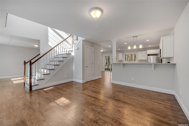 unfurnished living room featuring dark wood finished floors, stairs, and baseboards