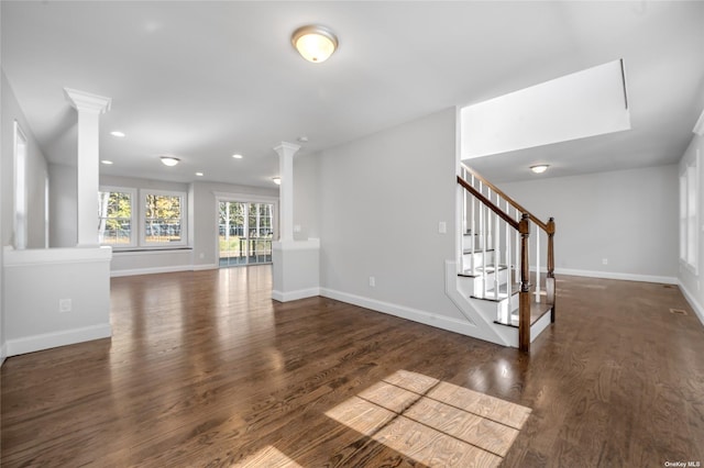 interior space featuring wood finished floors, stairs, baseboards, and decorative columns