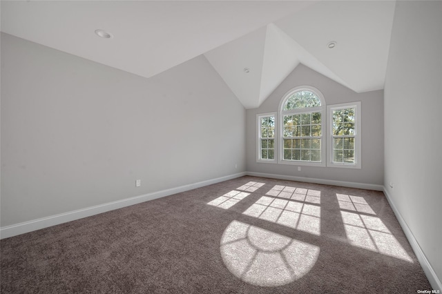 carpeted spare room featuring vaulted ceiling