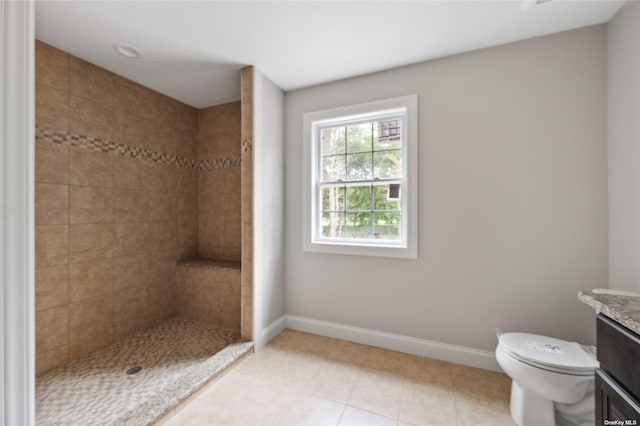 full bath with vanity, baseboards, a tile shower, tile patterned flooring, and toilet